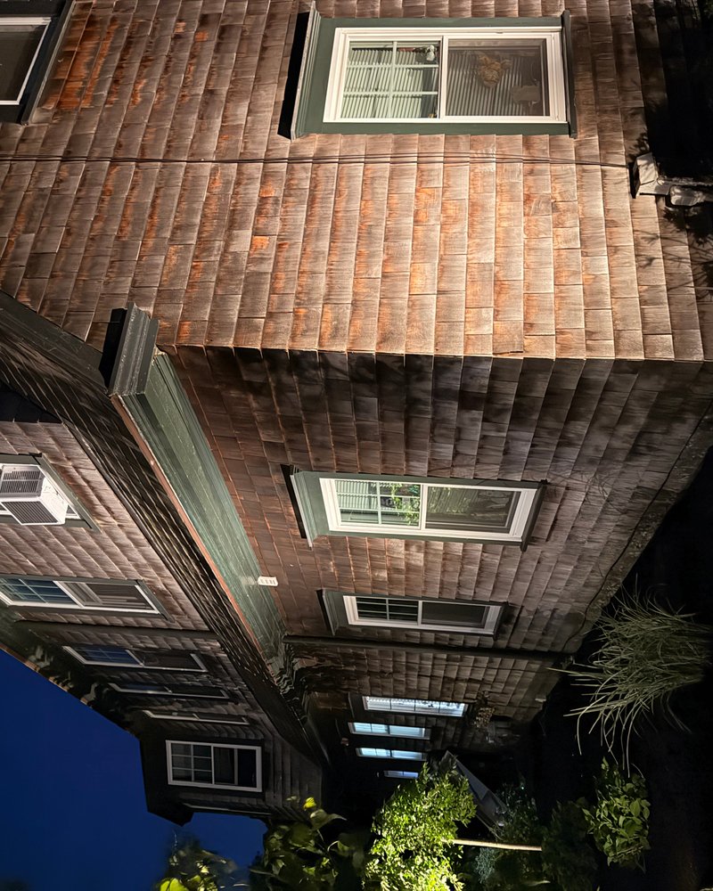 Cedar shingle facade lit at night showing warm texture and architectural detail, North Kingston RI